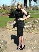 Gorgeous blonde MILF wearing a pretty black blouse and skirt, with matching pantyhose and tall stiletto heels
